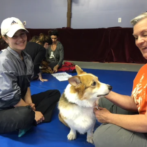 two women playing with a corgi